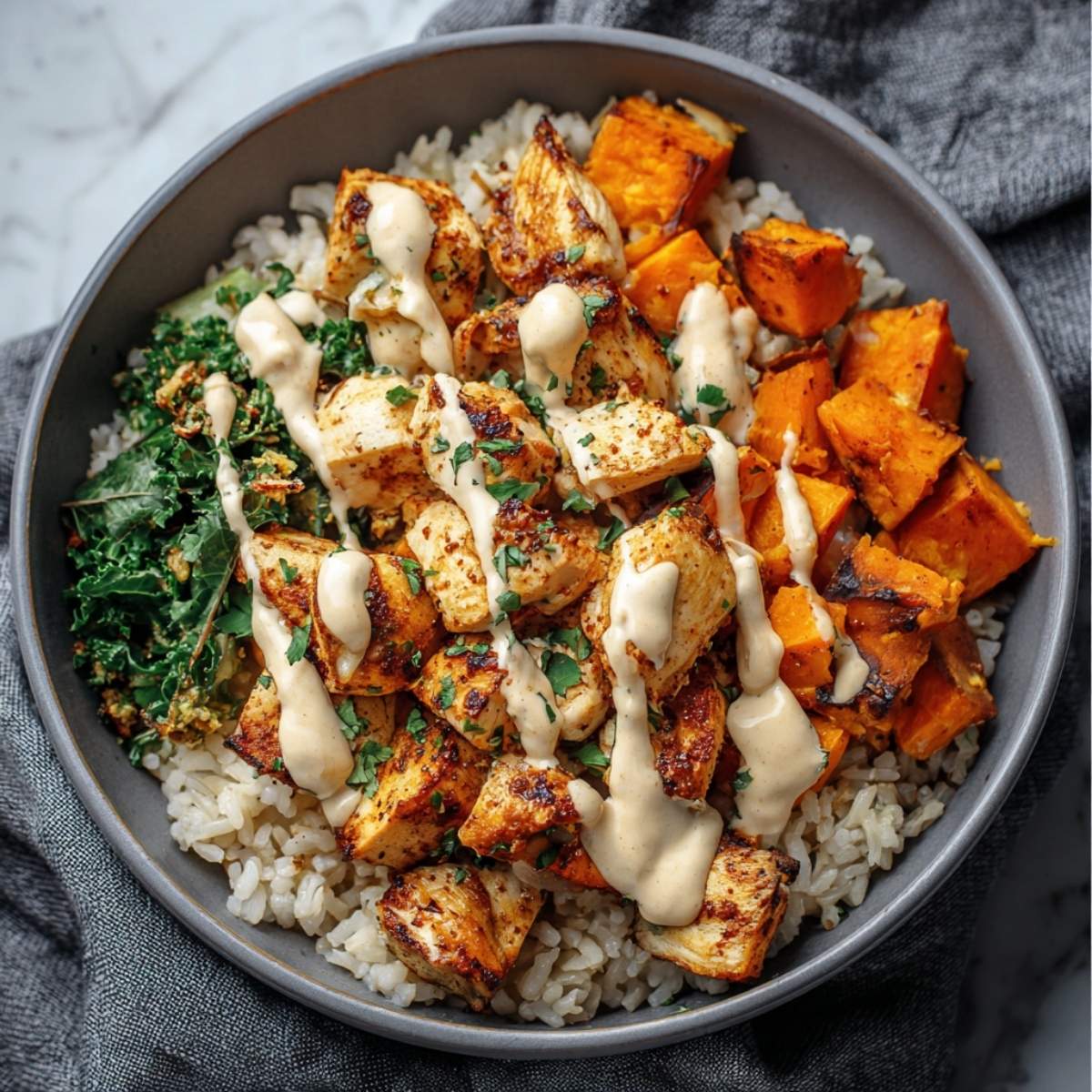 Chicken and Sweet Potato Rice Bowl in a grey bowl, showcasing roasted sweet potatoes and seared chicken on a bed of rice with kale