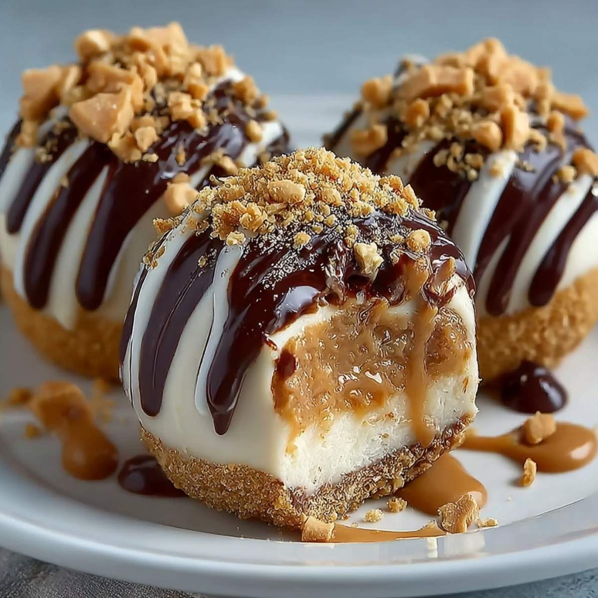 Peanut Butter Cheesecake Balls on a modern marble countertop, showcasing its creamy interior and chocolate drizzle with crushed peanuts