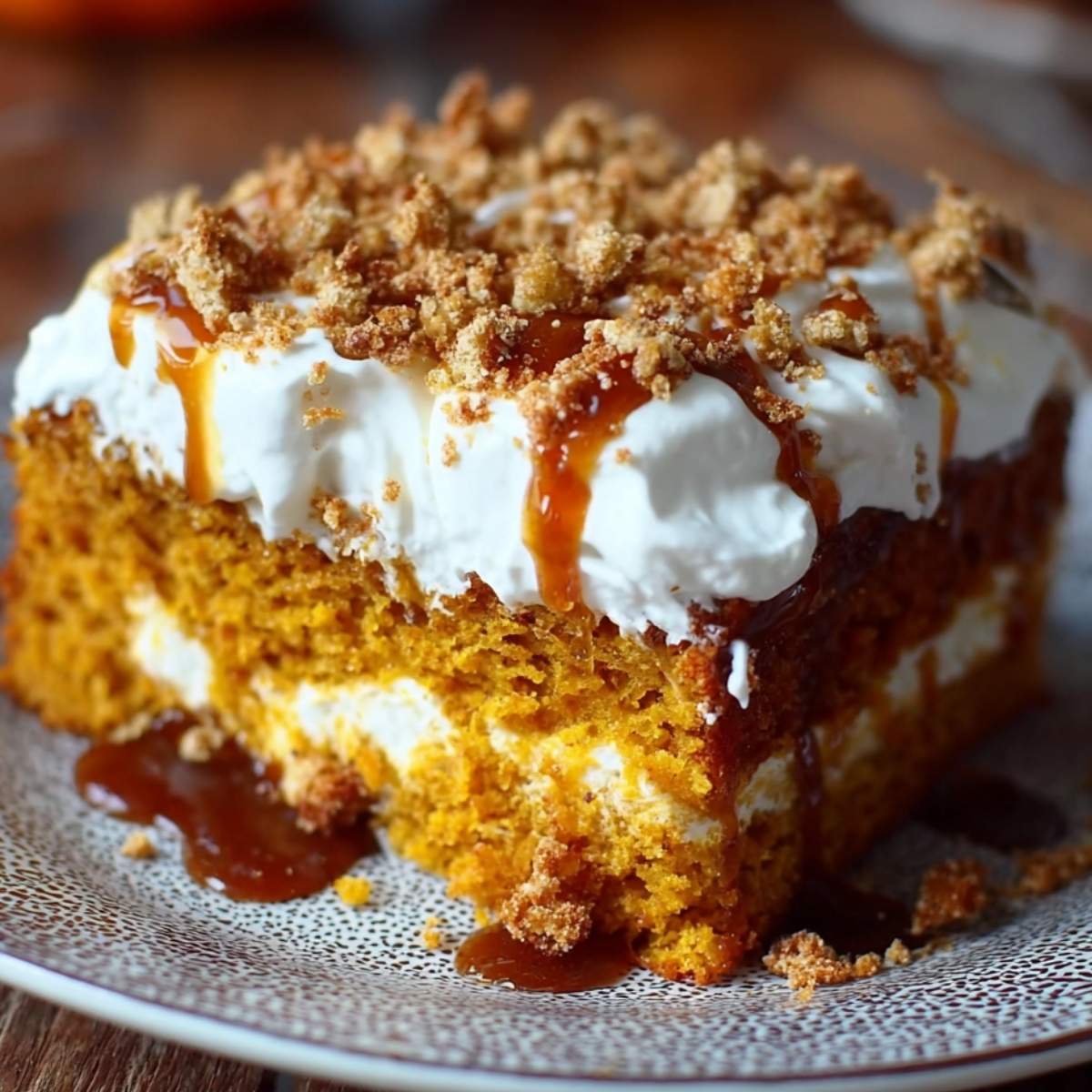 A slice of Pumpkin Better Than Any Cake on a plate, showing its moist layers, white topping, and rich caramel drizzle