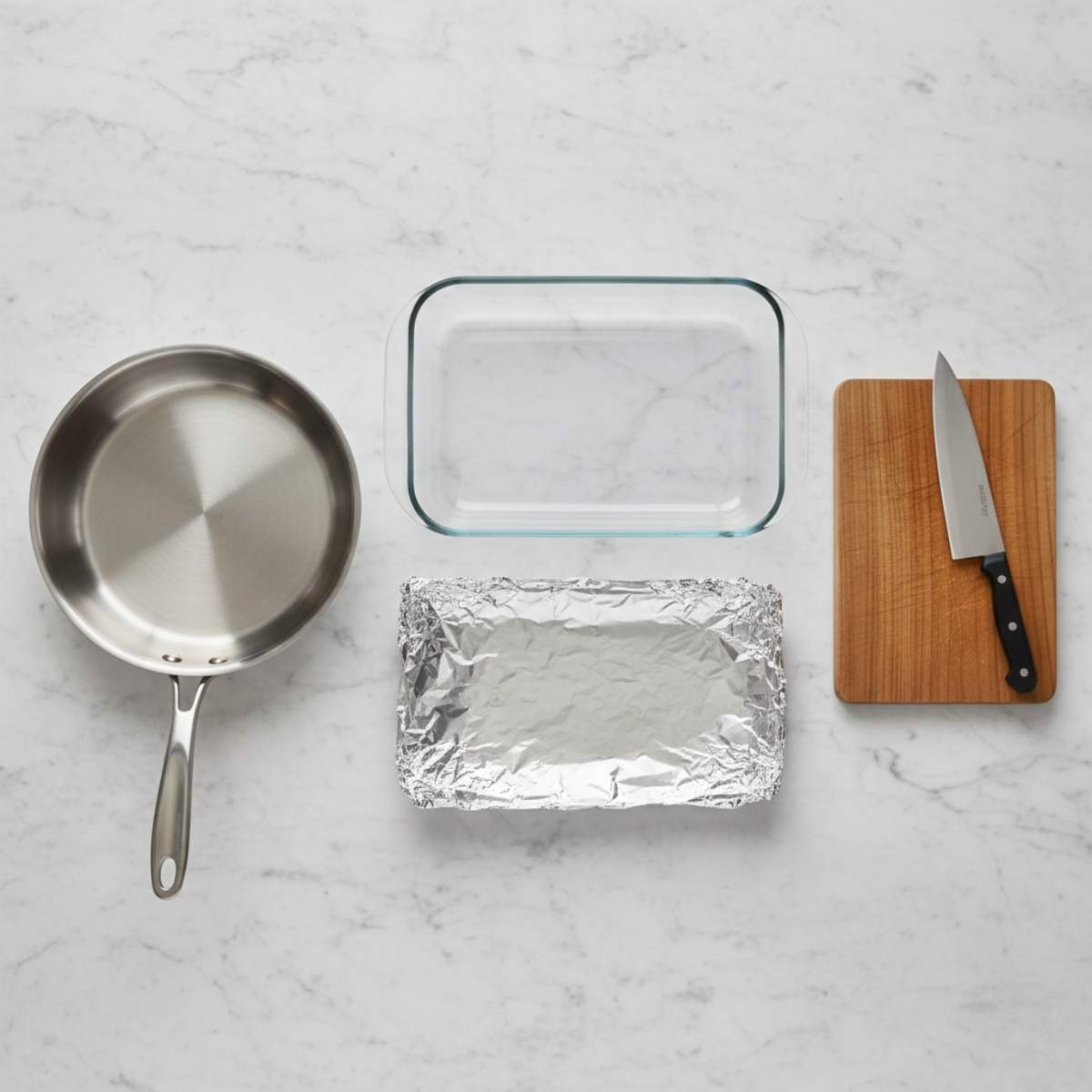 Kitchen tools for Cheesy Ground Beef and Potato Casserole including skillet, baking dish, foil tray, and cutting board on marble surface.