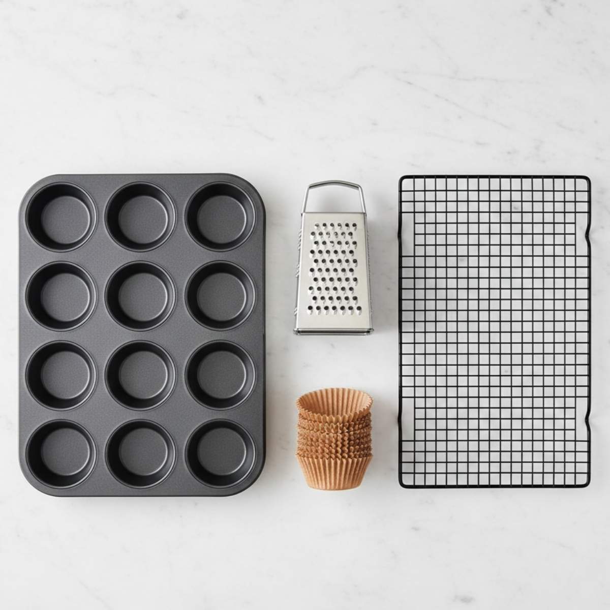 Baking equipment for Healthy Chocolate Zucchini Muffins including muffin tin, box grater, paper liners, and cooling rack