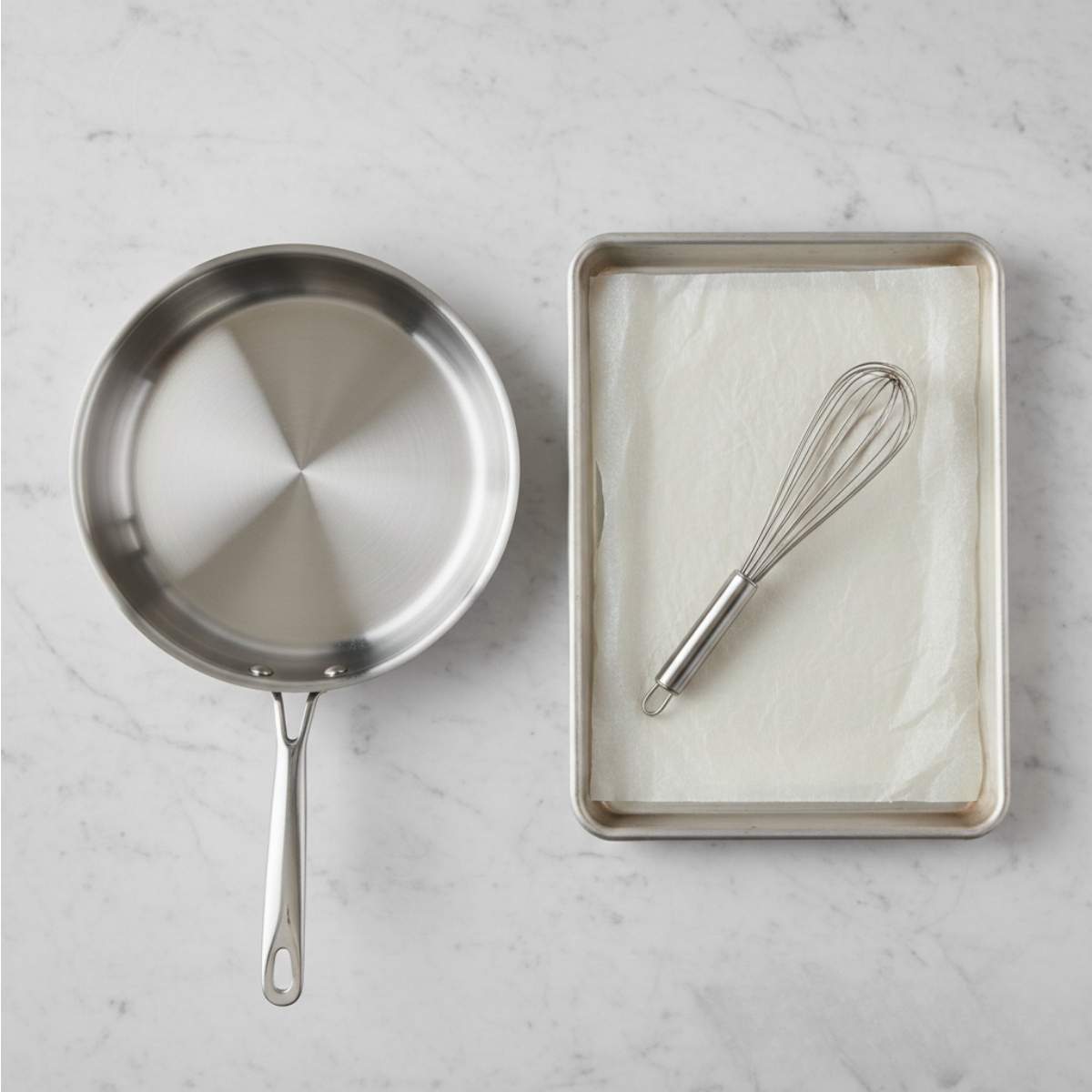 Cooking tools for sausage egg breakfast roll-ups including stainless skillet, parchment-lined baking sheet, and wire whisk.