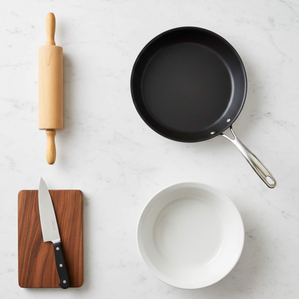 Kitchen tools for Sausage French Toast Roll-Ups including rolling pin, skillet, knife, cutting board, and mixing bowl on marble surface